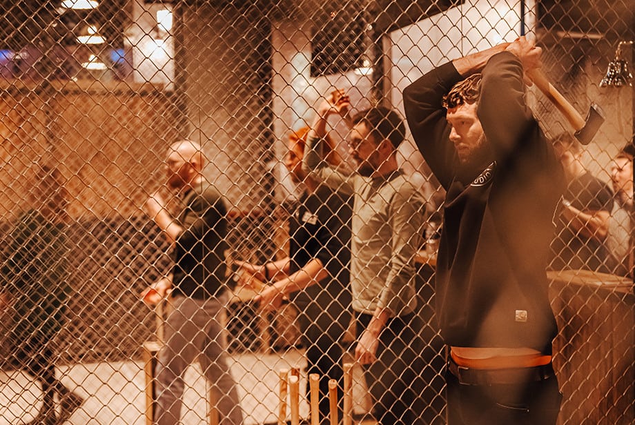 A group of men receiving axe throwing instruction from a Whistle Punks staff member