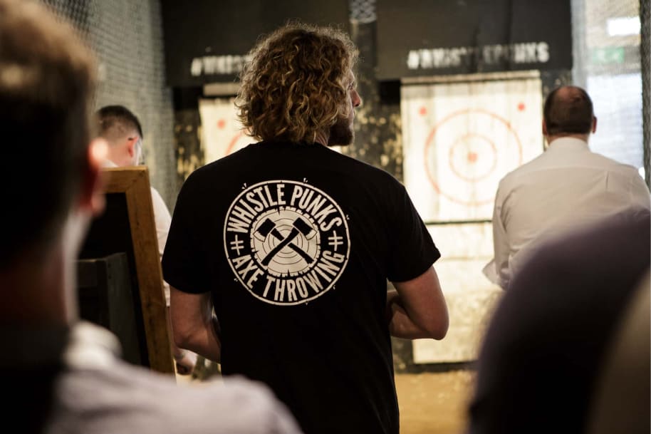 Whistle Punks staff member watching visitors throw axes